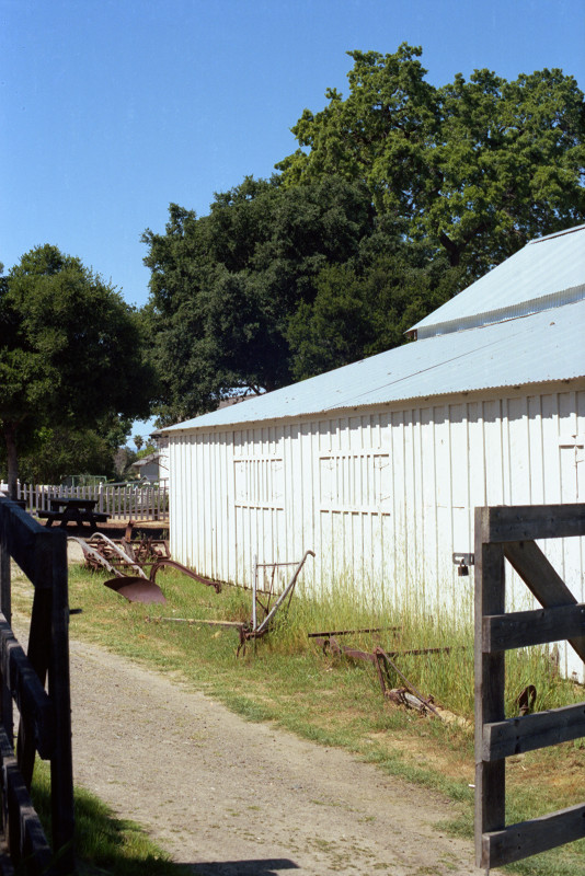 The old wooden gate was opened, so I could wander into the paddock at the Bernal Ranch. Old farm implements are lined up in a little grassy area next the barn.