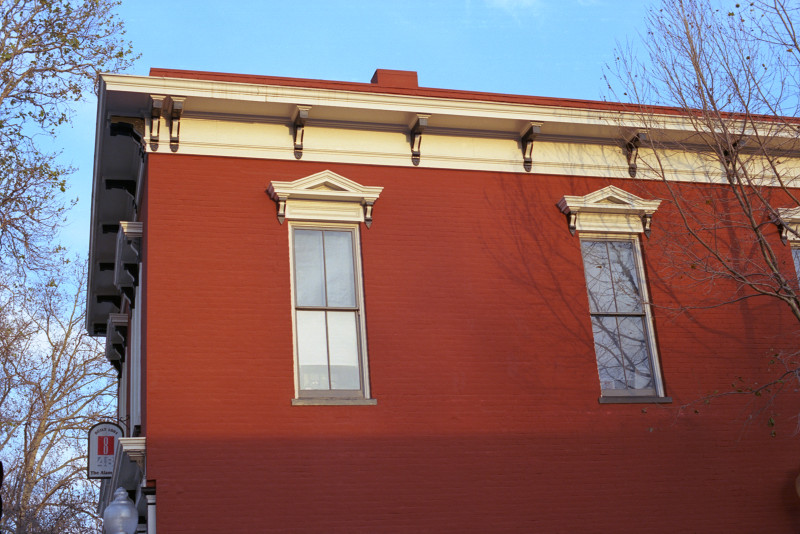 Red ochre brick building, showing two windows on the second floore, the building in Federalist period style. The Alameda, San José.