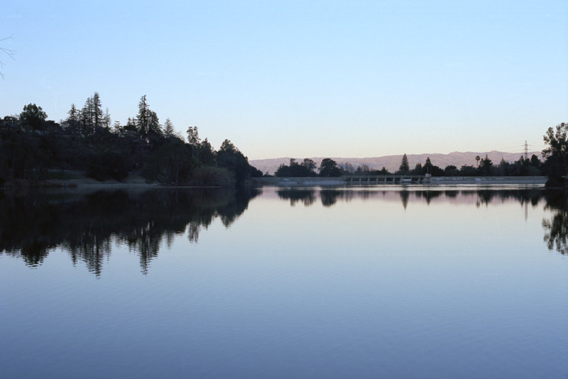 All in silhouette in late afternoon at Vasona Park. A transmission tower at right; the dam at northern end of the Lake just visible. Beyond that, the mountains east of San José, the highest point at Lick Observatory on Mount Hamilton, 4100 feet elevation.